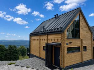 a wooden cabin with a metal roof and a large door at Góry i Chmury in Duszniki Zdrój