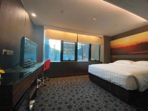 a bedroom with a bed and a desk with a television at J Link Hotel in Hong Kong