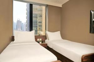 two beds in a room with a large window at J Link Hotel in Hong Kong