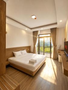 a bedroom with a bed and a large window at AuraLite Hotel - Panorama View Đà Lạt in Da Lat