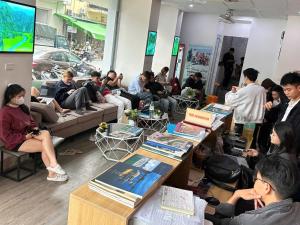 a group of people sitting in a room with tables at Ha Noi Capsule Station Hostel in Hanoi