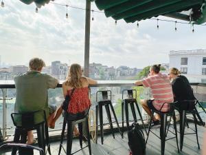 a group of people sitting on bar stools on a balcony at Ha Noi Capsule Station Hostel in Hanoi