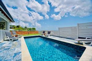 a swimming pool with chairs next to a house at Villa T4 La Sagesse WS - Piscine Privée in Rivière-Salée