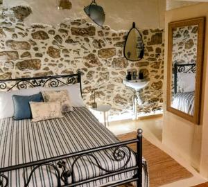 a bedroom with a bed and a stone wall at St Thomas House in Adhráktia
