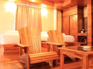 two wooden chairs and a table in a room at Srisawat Resort in Cha Am