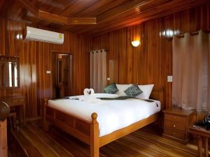 a bedroom with a large white bed with wooden walls at Srisawat Resort in Cha Am