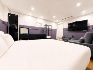 a bedroom with a bed and a tv and a couch at Hotel Yaja Gwangalli in Busan