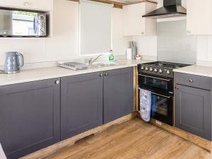 a kitchen with blue cabinets and a sink and a stove at Astra - Ukc9718 in Aston
