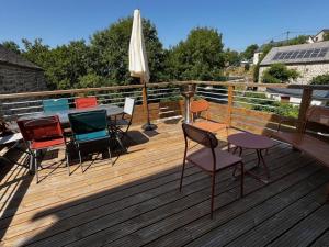 a deck with chairs and a table and an umbrella at Gîte de l'escapade in Rieutort