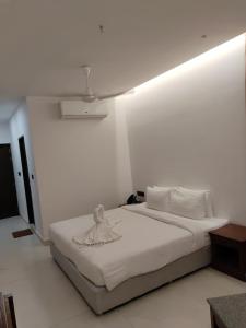 a white bedroom with a bed in a room at Hotel Elite International in Trichūr