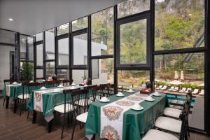 a dining room with green tables and chairs and windows at Cát Bà Sena Valley Retreat in Xuan Dam