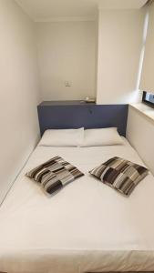 a white bed with two black and white pillows on it at Goodrich Hotel in Hong Kong +97 photos