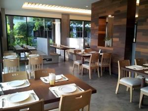 a restaurant with wooden tables and chairs and windows at Klim Hotel in Buriram