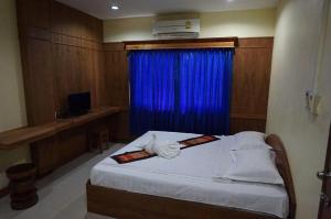 a bedroom with a bed with a blue curtain at Lankham Hotel in Pakse