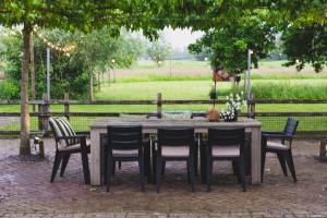 a wooden table and chairs with a field in the background at Stijlvol 4-6 pers "Vakantiehuis De Meierij" - compleet ingericht huis met vrij weidezicht in Schijndel