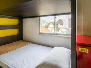 a small bedroom with a bed and a window at G4 Station Backpackers Hostel in Singapore