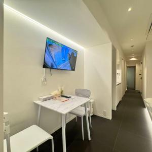 a room with a white table and a tv on the wall at MARUKOUHOTEL 入船 inn in Tokyo