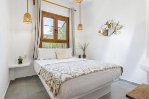a white bedroom with a bed and a window at Amaranthos Garden Retreat in Skopelos Town