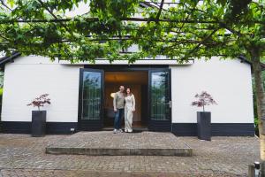 a man and woman standing in front of a building at Stijlvol 4-6 pers "Vakantiehuis De Meierij" - compleet ingericht huis met vrij weidezicht in Schijndel