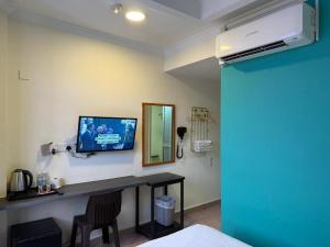 a room with a tv on a wall with a table at Darlene Hotel in Singapore