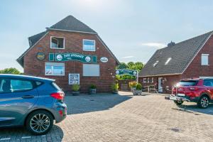 two cars parked in front of a brick building at Hotel Zum Wikinger - Haustiere in Dornum
