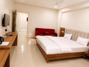 a bedroom with a bed and a red chair at Hotel The Amrit in Jabalpur