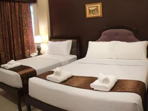 two beds in a hotel room with towels on them at Peridot Suites in Buhangin