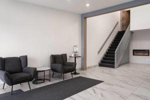 a lobby with two chairs and a table and stairs at Travelodge by Wyndham Drummondville in Drummondville