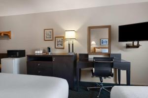 a hotel room with a desk and a bed and a mirror at Travelodge by Wyndham Drummondville in Drummondville