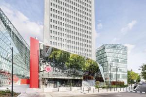 a building with a glass facade next to two tall buildings at H4 Wyndham Paris Pleyel in Saint-Denis