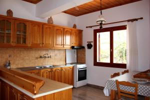 a kitchen with wooden cabinets and a table and a window at Theros Beach House in Stavros