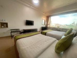a hotel room with three beds and a window at Grand Harbour Hotel in Macau