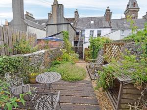 a garden with a wooden pathway with chairs and a table at The Beltie Flat in Newton Stewart