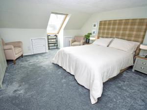 a bedroom with a large white bed and two chairs at The Beltie Flat in Newton Stewart
