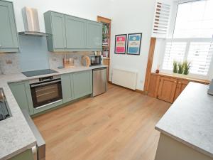 a kitchen with green cabinets and a wooden floor at The Beltie Flat in Newton Stewart