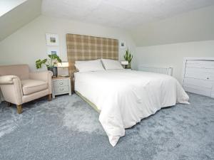 a bedroom with a large white bed and a chair at The Beltie Flat in Newton Stewart