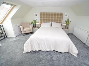 a bedroom with a large white bed and a chair at The Beltie Flat in Newton Stewart +8 photos