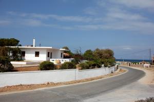 an empty road in front of a white house at Theros Beach House in Stavros