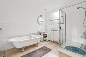 a white bathroom with a tub and a sink at Gunyha - Ocean Views, Walk to Beach, Free WiFi, Pet Friendly, Open Fire, Visiting Koalas and Other Wildlife. in Apollo Bay +15 photos