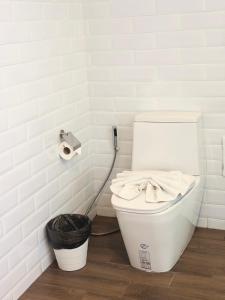 a white toilet in a bathroom with a roll of toilet paper at โรงแรม เดอะโมเดล การ์เด้น in Yasothon