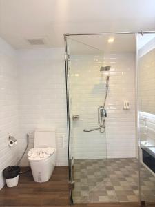 a bathroom with a toilet and a glass shower at โรงแรม เดอะโมเดล การ์เด้น in Yasothon