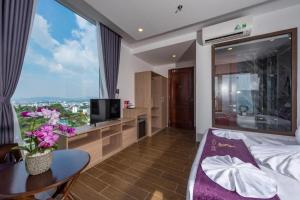 a hotel room with a bed and a tv and a table at Maison Hotel Phu Quoc in Phú Quốc