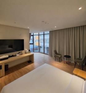 a living room with a large television and a living room with chairs at Stayrak Hotel in Seoul