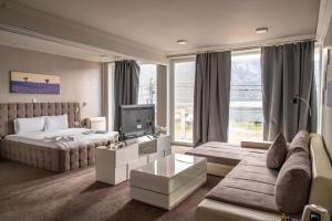a bedroom with a bed and a couch and a tv at La Vella Resort in Dubova +44 photos