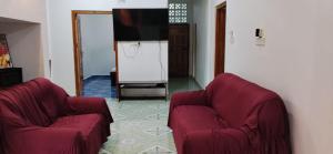 a living room with two red chairs and a flat screen tv at Trinco Harbour Villa in Trincomalee