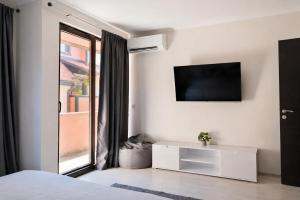 a white bedroom with a tv on the wall at Medius Park Apartment in Sandanski