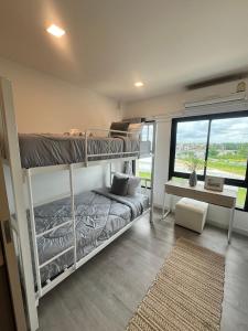 a bedroom with two bunk beds and a desk at The Eiffel Cafe and Hotel in Ban Khlong Lat Bua Khao