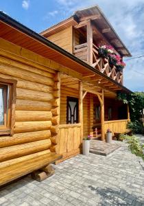 a wooden house with a patio in front of it at «У полоні гір» in Verkhovyna