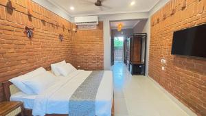 a bedroom with a brick wall with a bed and a tv at Hide Away Resort in Jhārgrām