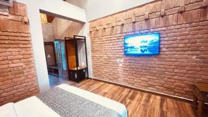a bedroom with a brick wall and a tv on a wall at Hide Away Resort in Jhārgrām +27 photos